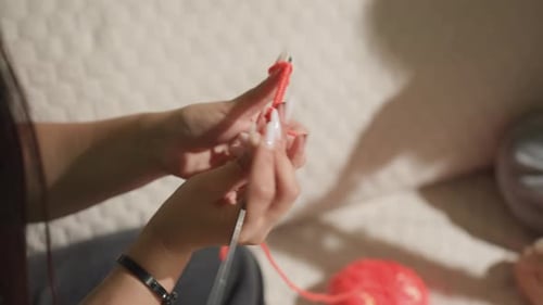 Woman knitting with orange yarn at home