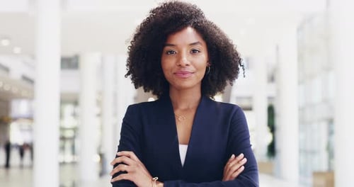 Young, confident and professional business woman laughing while standing in the office with her arms