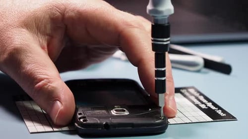 Hand Unscrews Screws From Black Cell Phone