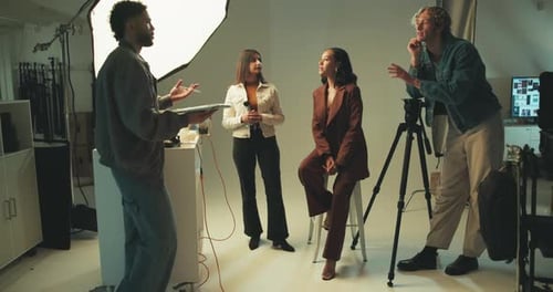 Photography, man and talking to models in studio for production or director planning photoshoot