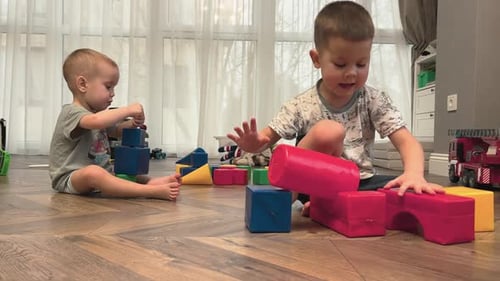 Two Children Joyfully Playing with Colorful Building Blocks in a Cozy Creative Space