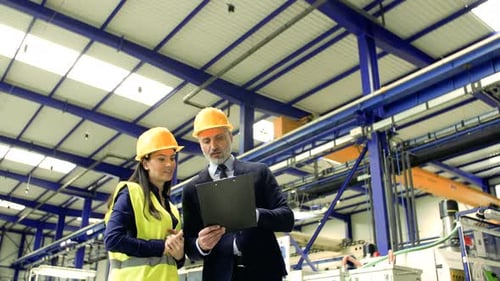 Industrial Man and Woman Engineers with Board in a Factory Working