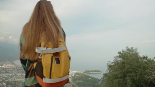 Woman Overlooking Scenic Coastline From Mountain Top