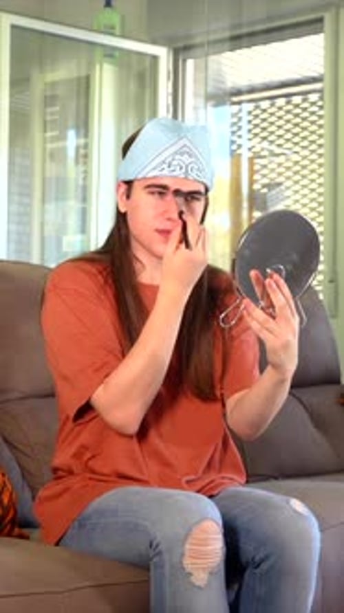 Young Adult Applying Makeup with Brush and Mirror