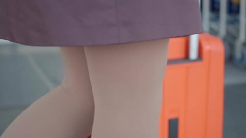 Mulher em meias de compressão andando com a mala na entrada do aeroporto ao ar livre