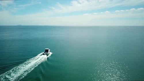 Aerial rising shot, following from behind of a speed boat travelling out to the ocean, created a bea