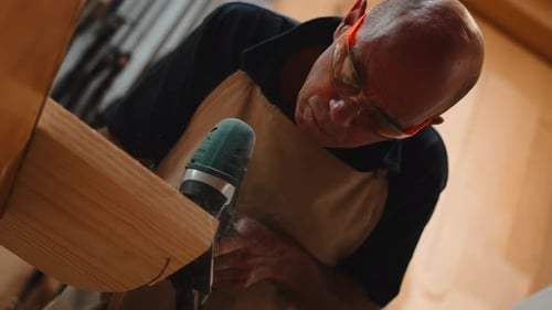 Professional Carpenter Drilling Wooden Beam in His Workshop with Power Tool