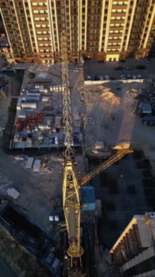 Vertical Video Tower Crane Working at Urban Construction Site at Sunset