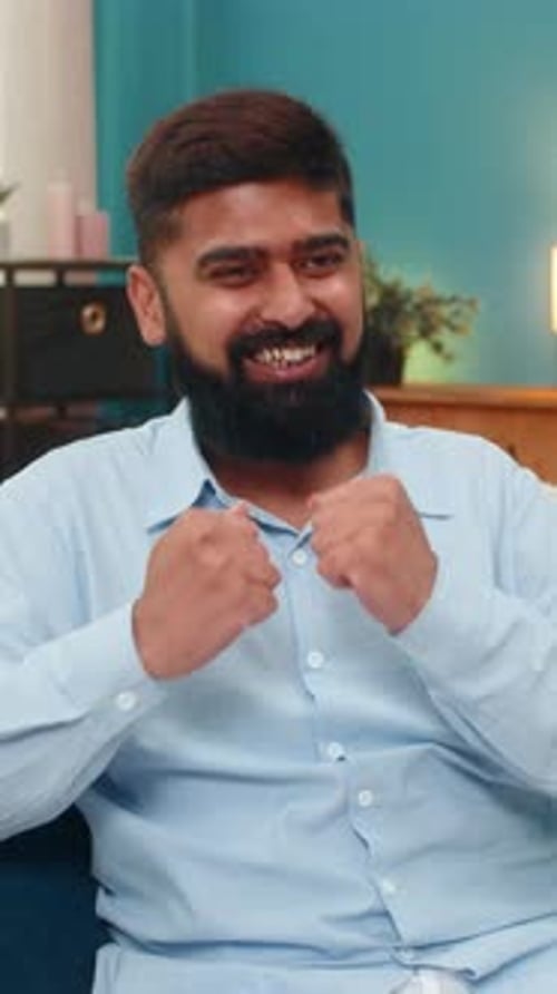 Enthusiastic Man Celebrates Success Indoors with Energetic Clapping