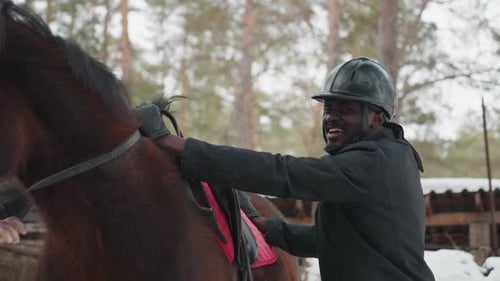 Man Adjusting Horse Tack Outdoors Near Forest on Winter Day