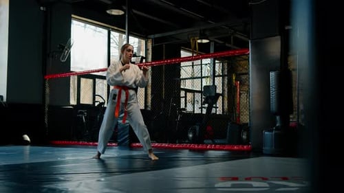 A girl practices karate in a gym A woman in kimono practices movements and poses Martial arts