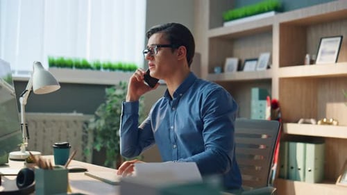 Young Adult Working and Talking on Phone in Office