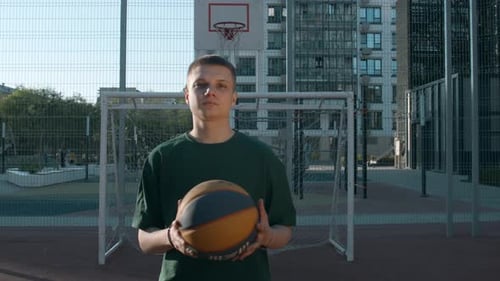 Young Adult Holds Basketball on Urban Court
