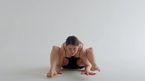 Junge Frau spielt Glühwürmchen-Pose während der Yoga-Praxis im Studio