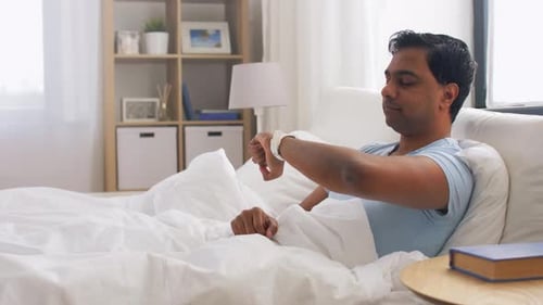 Man in bed using smart watch technology