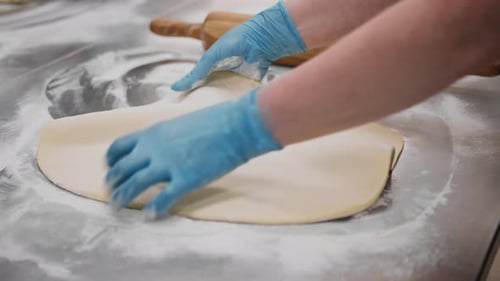 The kitchen in the bakery - the process of preparing cinnabons, the woman baker forms doughs