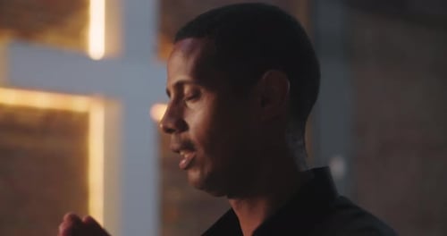 Young Adult Praying Before Christian Cross in Church