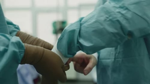 Nahaufnahme, nicht wiederzuerkennen, Chirurg, Mann, der OP-Handschuhe anzieht, männliche Hände, Arzt mit Assistent, Putten
