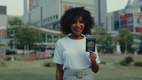Portrait of African American Woman Showing British Passport Against Business Center