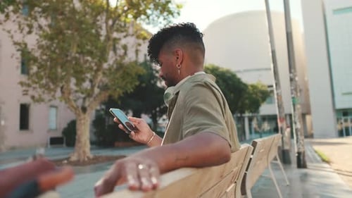 Young Adult Using Mobile Phone on Park Bench