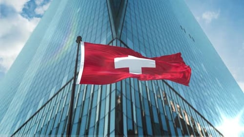 Swiss Flag Waving in Wind with Modern Corporate Skyscraper Background