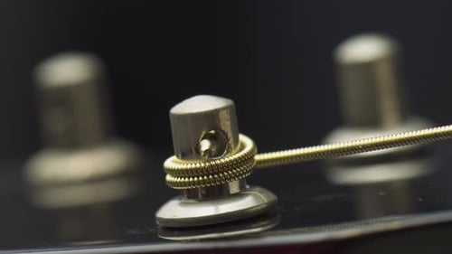 Closeup view of winding a new string onto guitar tuning peg