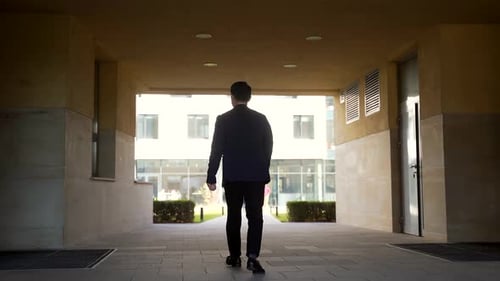 Die Silhouette eines asiatischen Geschäftsmannes von hinten geht im modernen Gewölbe den Korridor entlang