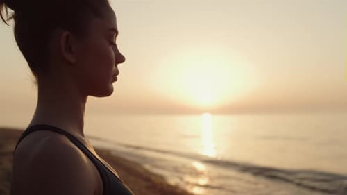 Sportswoman profile practicing yoga meditation on beach at sunrise for harmony