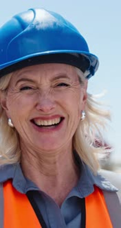 Construction, face and mature woman with smile on site, safety compliance and project management