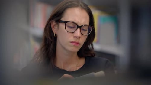 A Focused Young Woman Diligently Studying in a Peaceful Library Setting to Excel