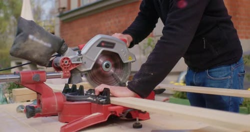 Adult Cutting Wood with Miter Saw Outside