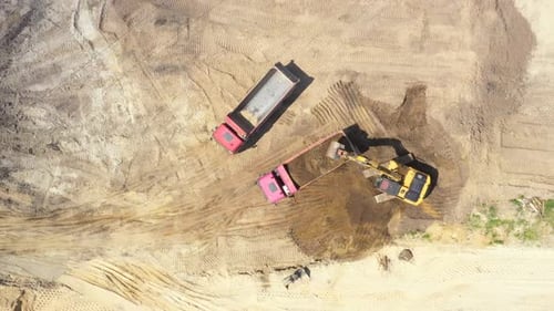 Blick von oben auf den Bagger, der Sand in einen Muldenkipper gießt. Bergbauindustrie