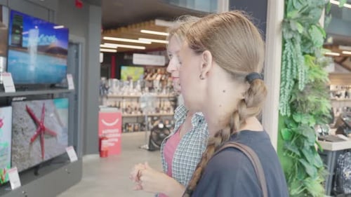 Women choosing new tv in electronics store