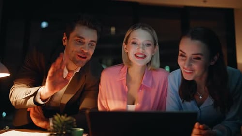 Friendly Colleagues Greeting Webcam Laptop Sitting at Night Office Closeup
