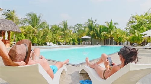 Couple Sunbath Lay On Sunbeds By Pool Relax On Vacation