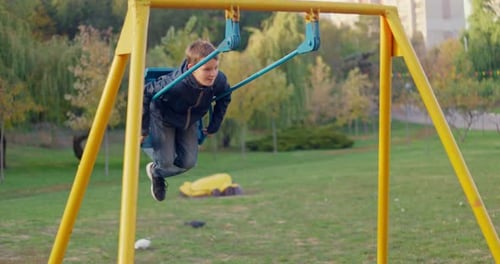 Boy Swinging on Swing Child Having Fun Playing in Outdoor Public Playground
