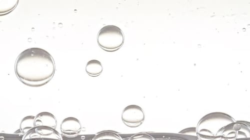 Foto macro de bolhas de ar transparente de tamanhos diferentes em água limpa subindo sobre o corpo de fundo branco