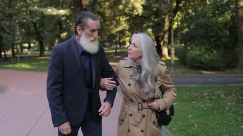 A Couple Walks Hand in Hand in a Park on a Sunny Day Enjoying Each Others Company