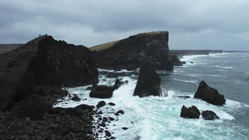Stormy ocean waves crashing on Icelandic black cliffs