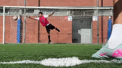 Goalkeeper dives to block soccer ball on field