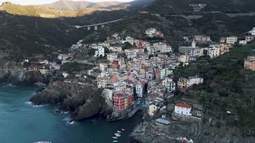 Aerial view of colorful houses and cliffs at sunset, Italy.