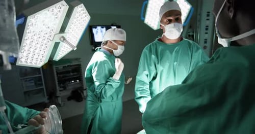 Diverse male and female surgeons operating on patient in operating theatre at hospital, slow motion