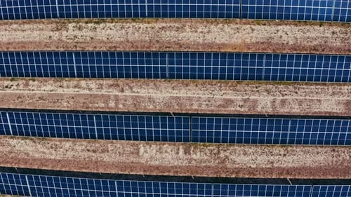 Eine Luftaufnahme von oben nach unten von Reihen von Sonnenkollektoren in einem großen Solarpark. Die klaren, symmetrischen Linien o