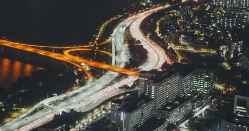Nighttime Aerial View of Illuminated Highways and Bridges Showcasing Flowing Traffic Patterns and