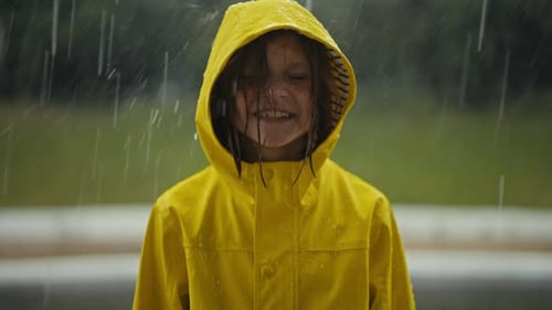 Child in Yellow Raincoat Smiling in the Rain