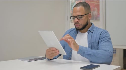 African Businessman with Loss on Tablet in Office