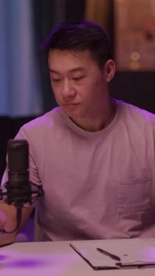 Un homme en chemise violette parle dans un micro en sirotant une tasse