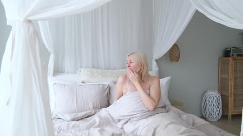 Blonde Woman Wakes Up, Stretches in Bed