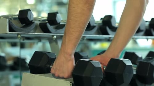 Closeup of Hands of a Young Man Who Takes to Perform Dumbbell