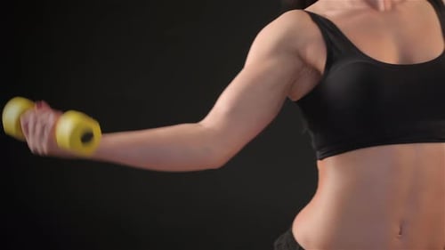 Fitness Woman Lifts a Dumbbell
